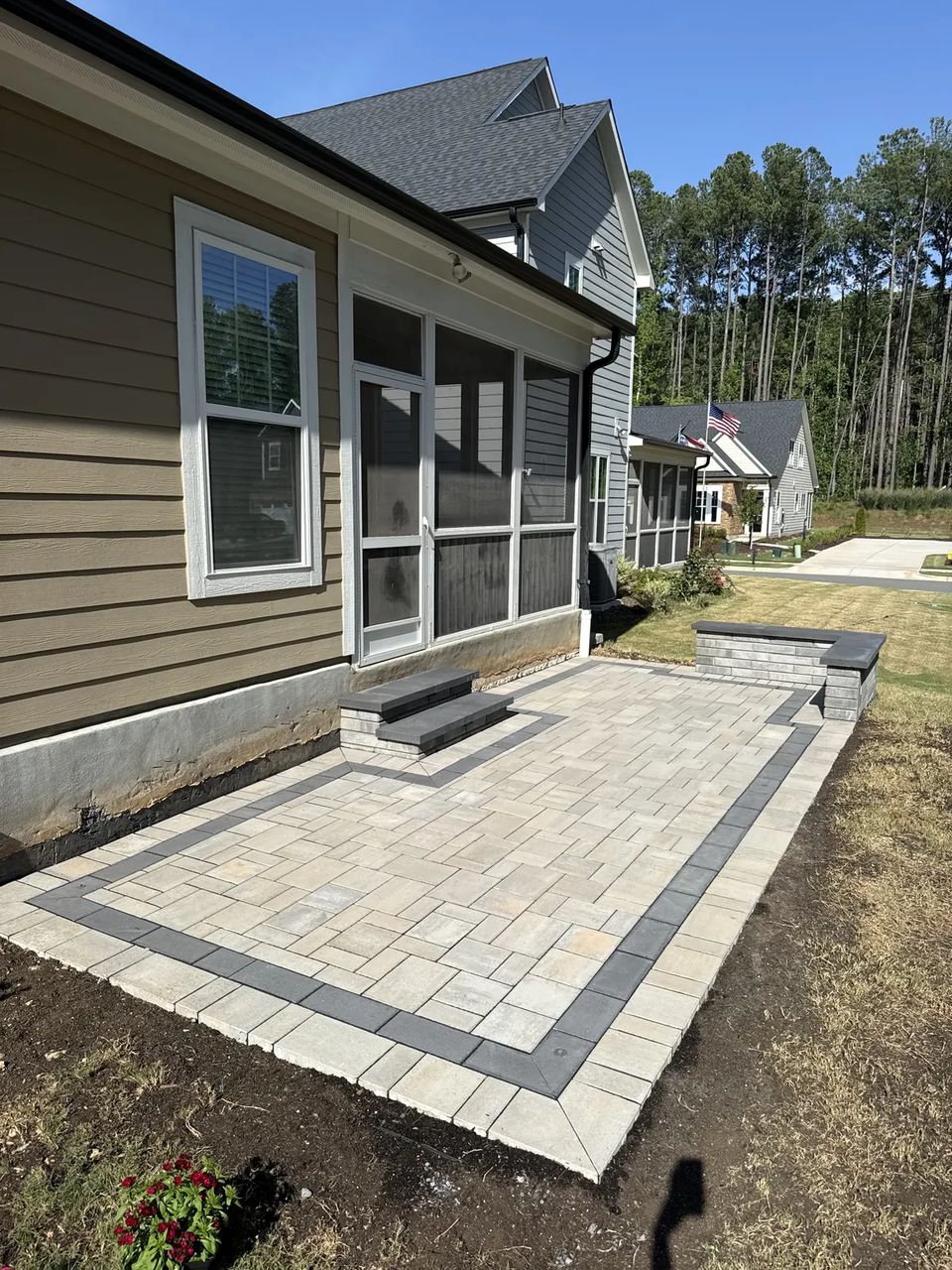 Paver patio with a dark border band below a screened porch