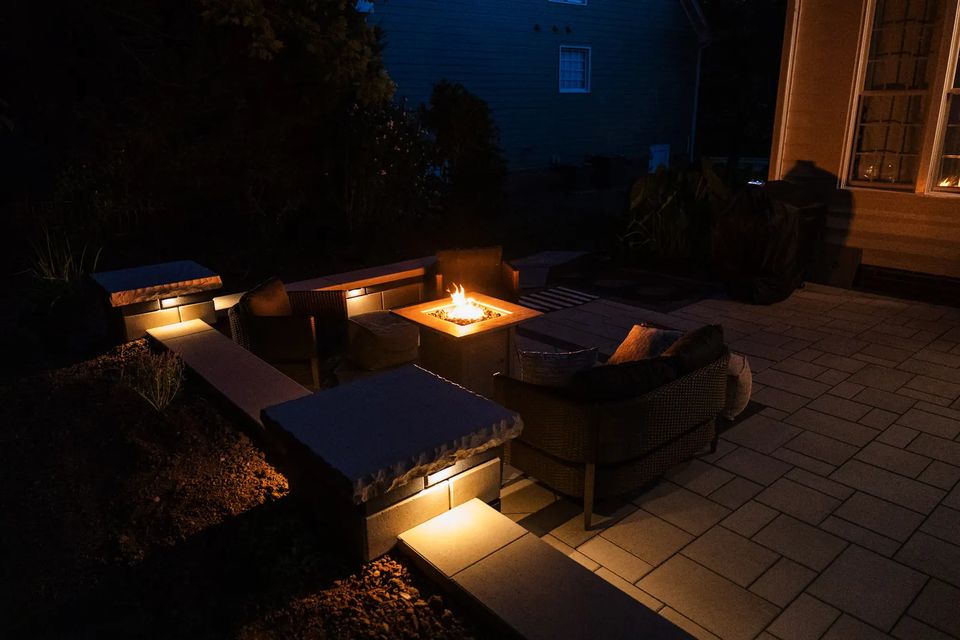 Wide night view of the sunken fire table lounge with glowing seat wall caps