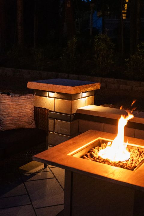 Gas fire table burning beside a lit stone pillar