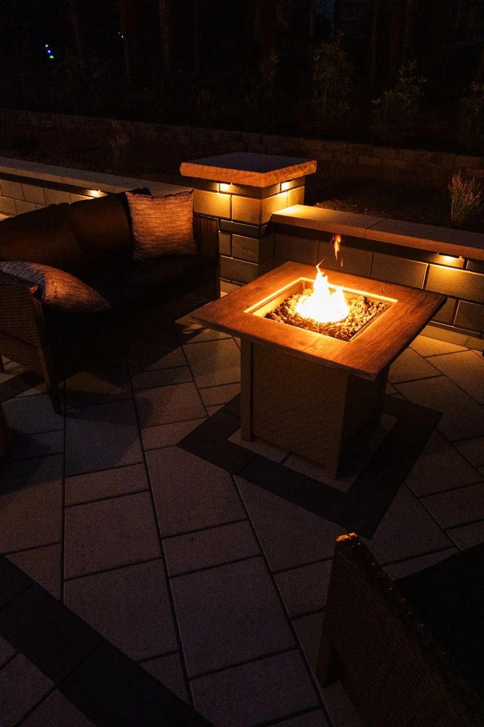 Fire table lounge framed by seat walls with cap lights
