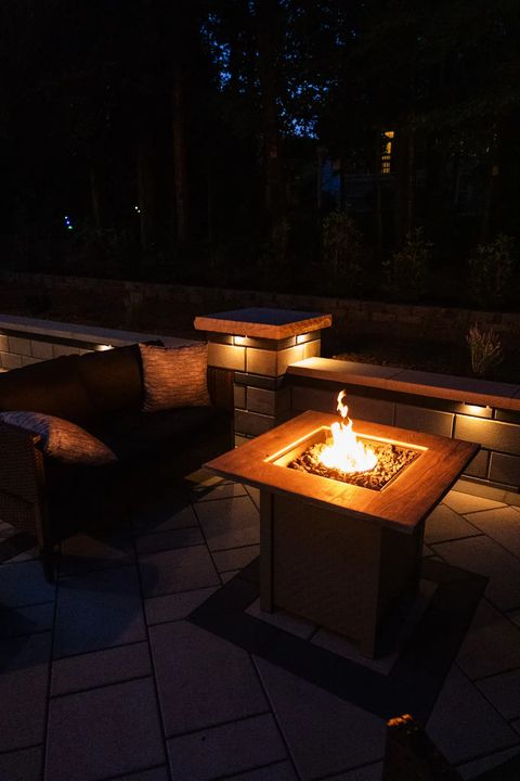Fire table in front of a lit seat wall at night