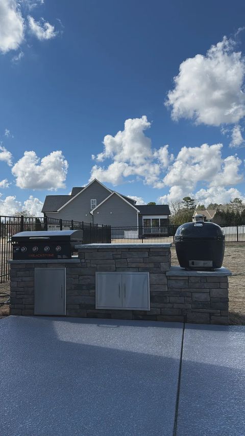 Stone veneer grill island with griddle and kamado on a new patio