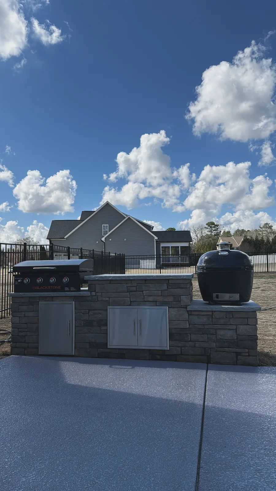 Stone veneer grill island with griddle and kamado on a new patio