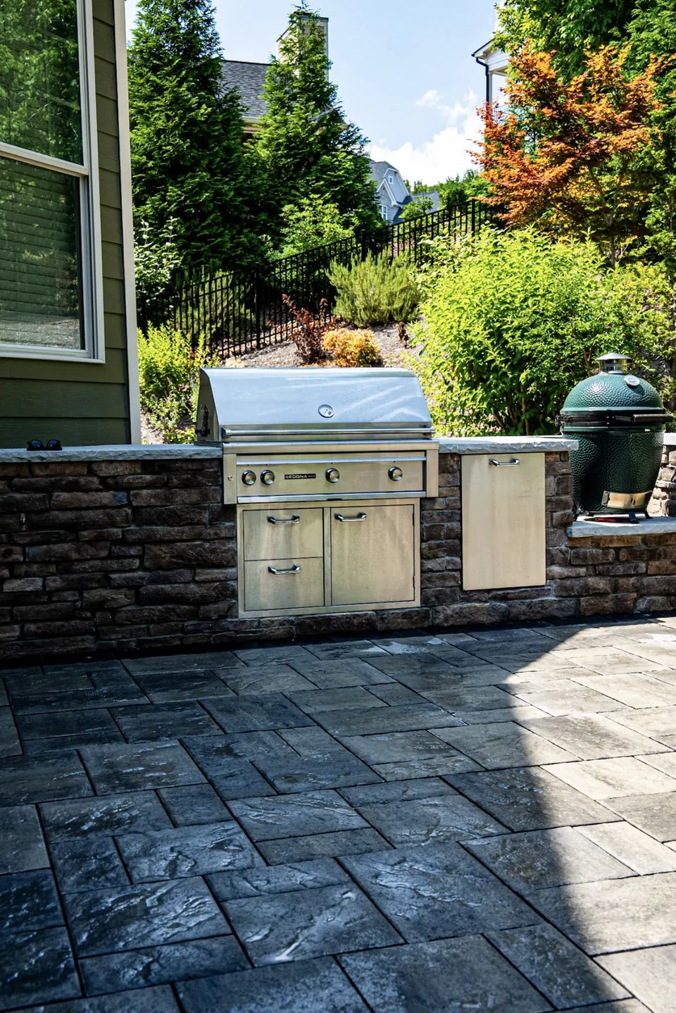 Kitchen patio with a built in grill, kamado and planted beds behind