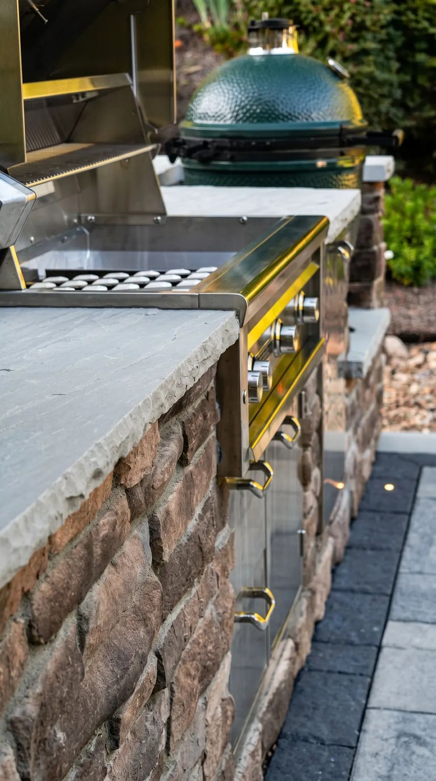 Stone veneer grill island with a stone counter and kamado