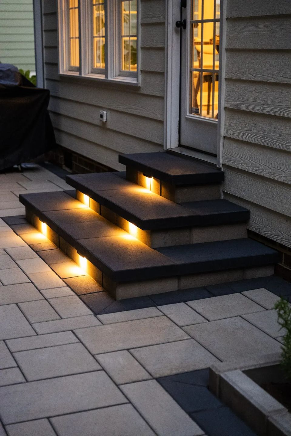 Lit paver steps down from the back door to the patio