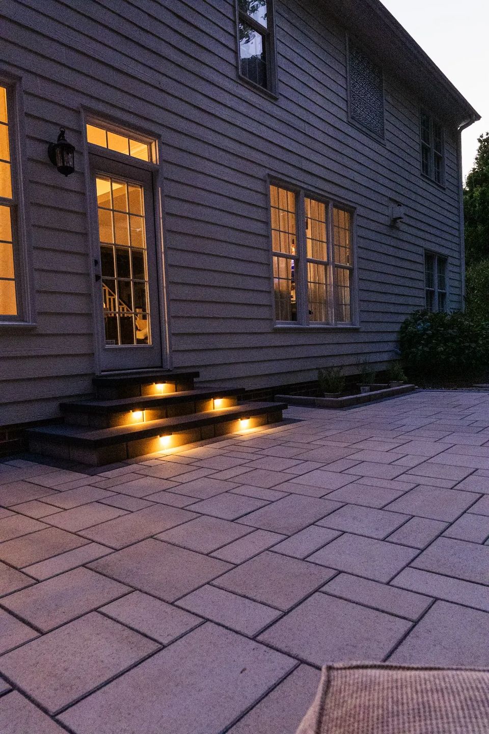 Lit steps and slab patio along the back of the house