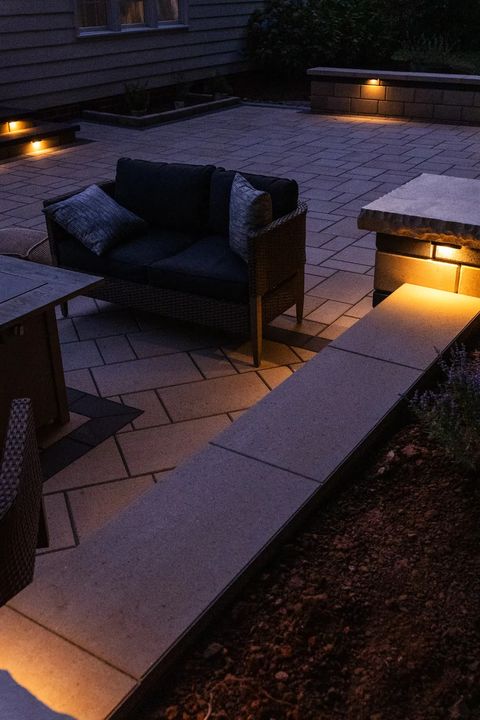 Seat wall with under cap lighting beside outdoor lounge furniture