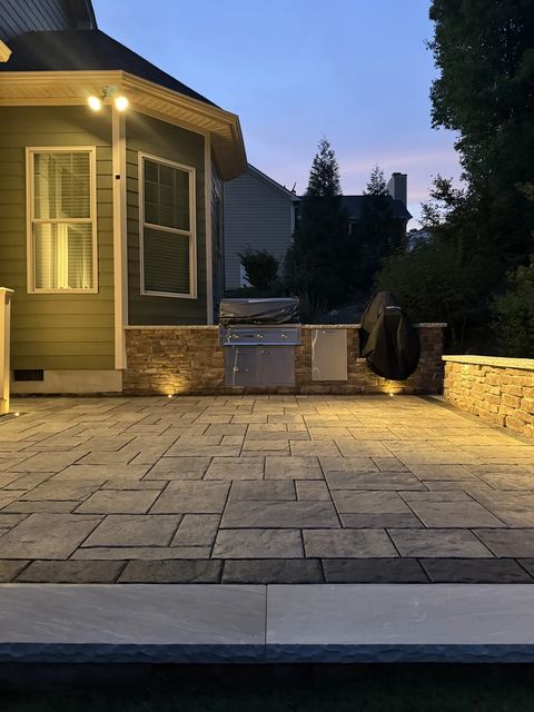 Kitchen patio lit at dusk with the grill island and porch steps