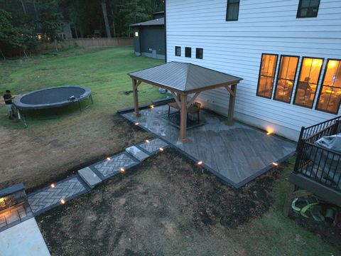 Pavilion patio and lit walkway behind the house at dusk