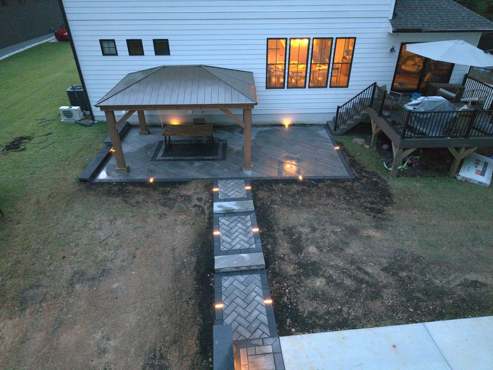 Lit herringbone walkway leading to a pavilion at twilight