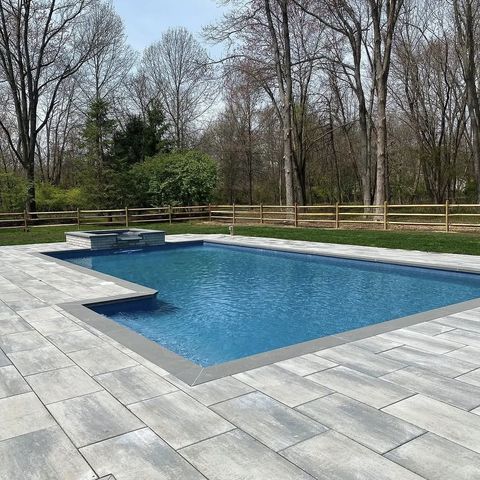 Paver pool deck around a pool with a raised spa
