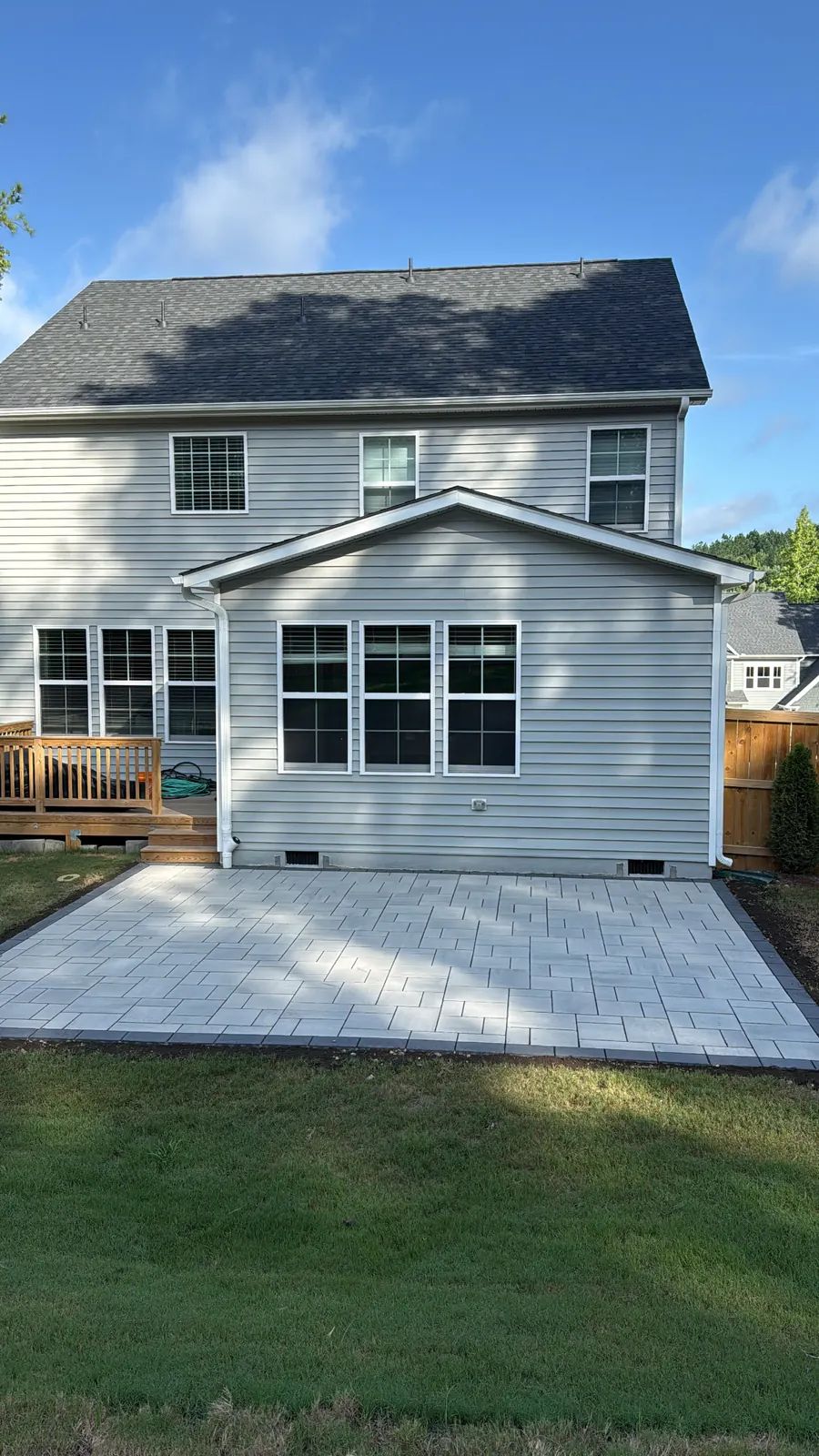Paver patio behind the house with pines in the background