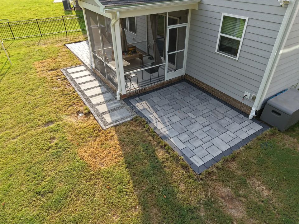 Paver patio along the side of a screened porch