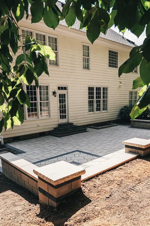 Slab patio with a contrasting square inlay and seat wall behind the house