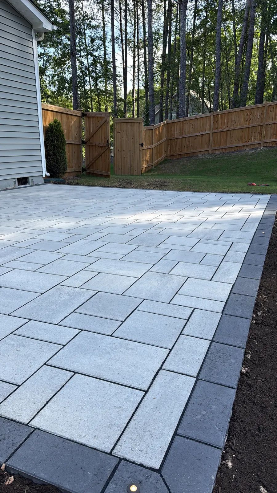 Large format slab patio along a wood fence
