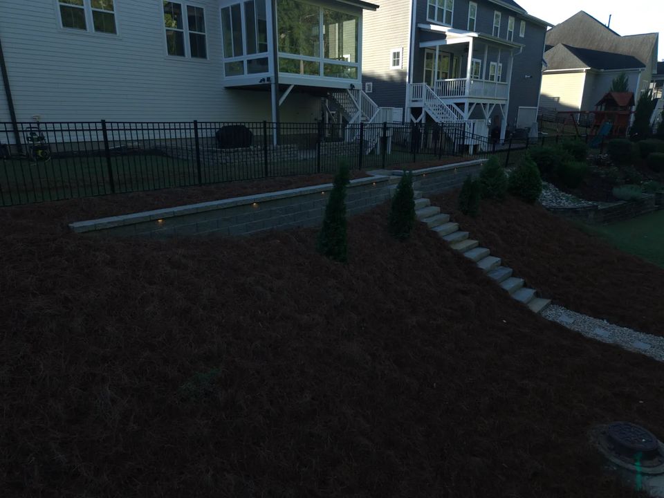 Retaining wall, stone stairs and planting beds on a fenced slope